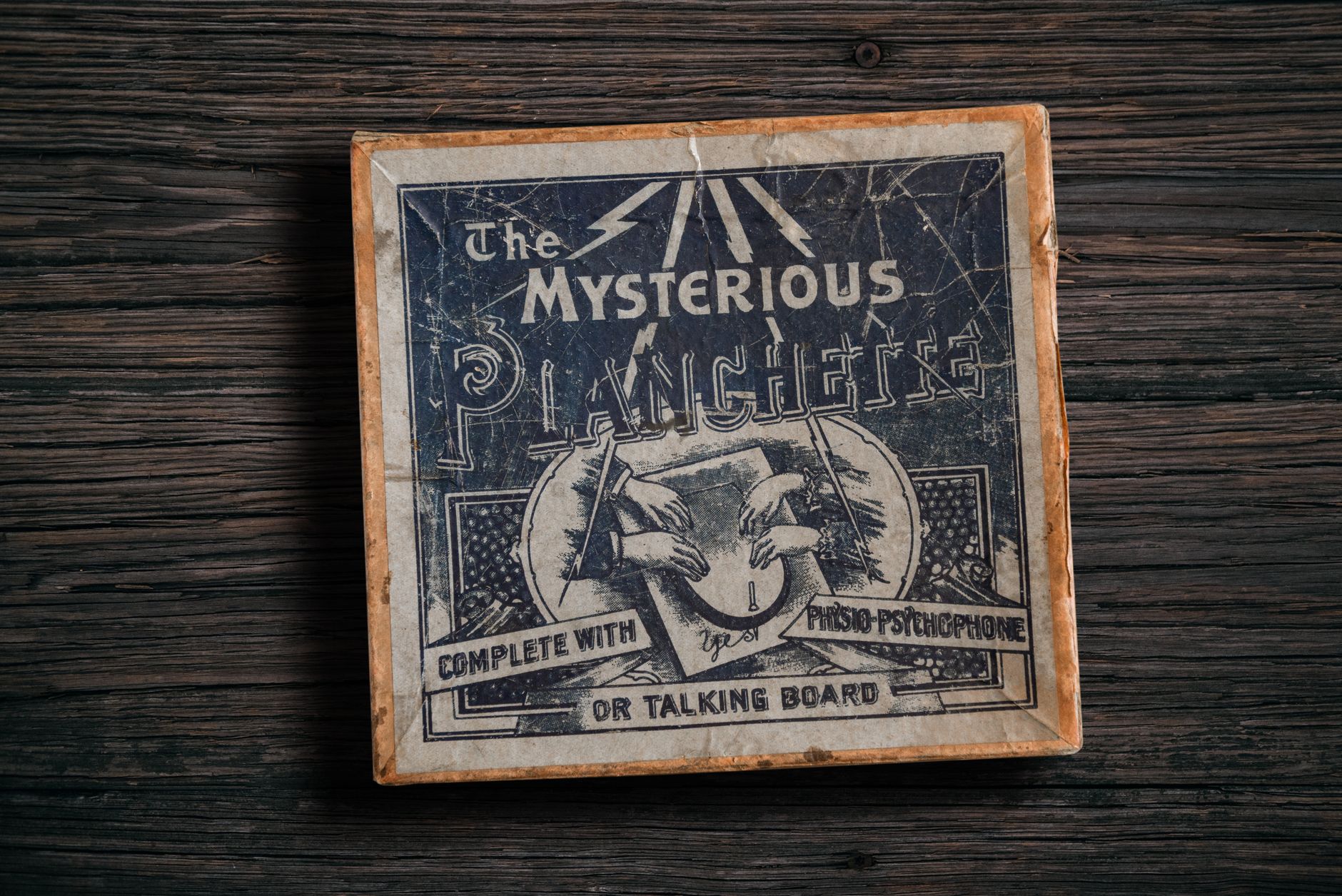 Antique mysterious planchette game board on rustic wooden surface.