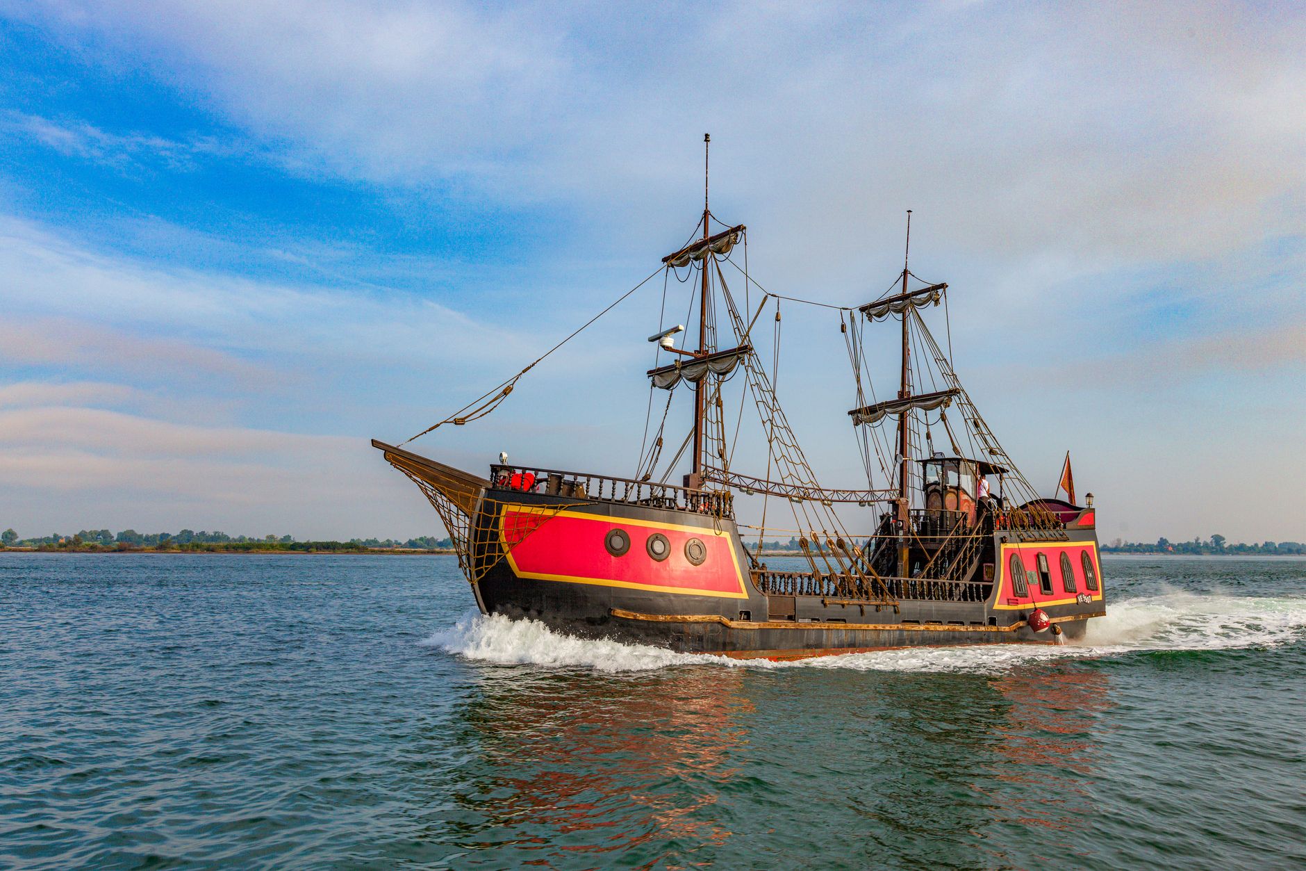A vibrant pirate ship sails on a clear day, showcasing its vintage wooden structure and colorful design.