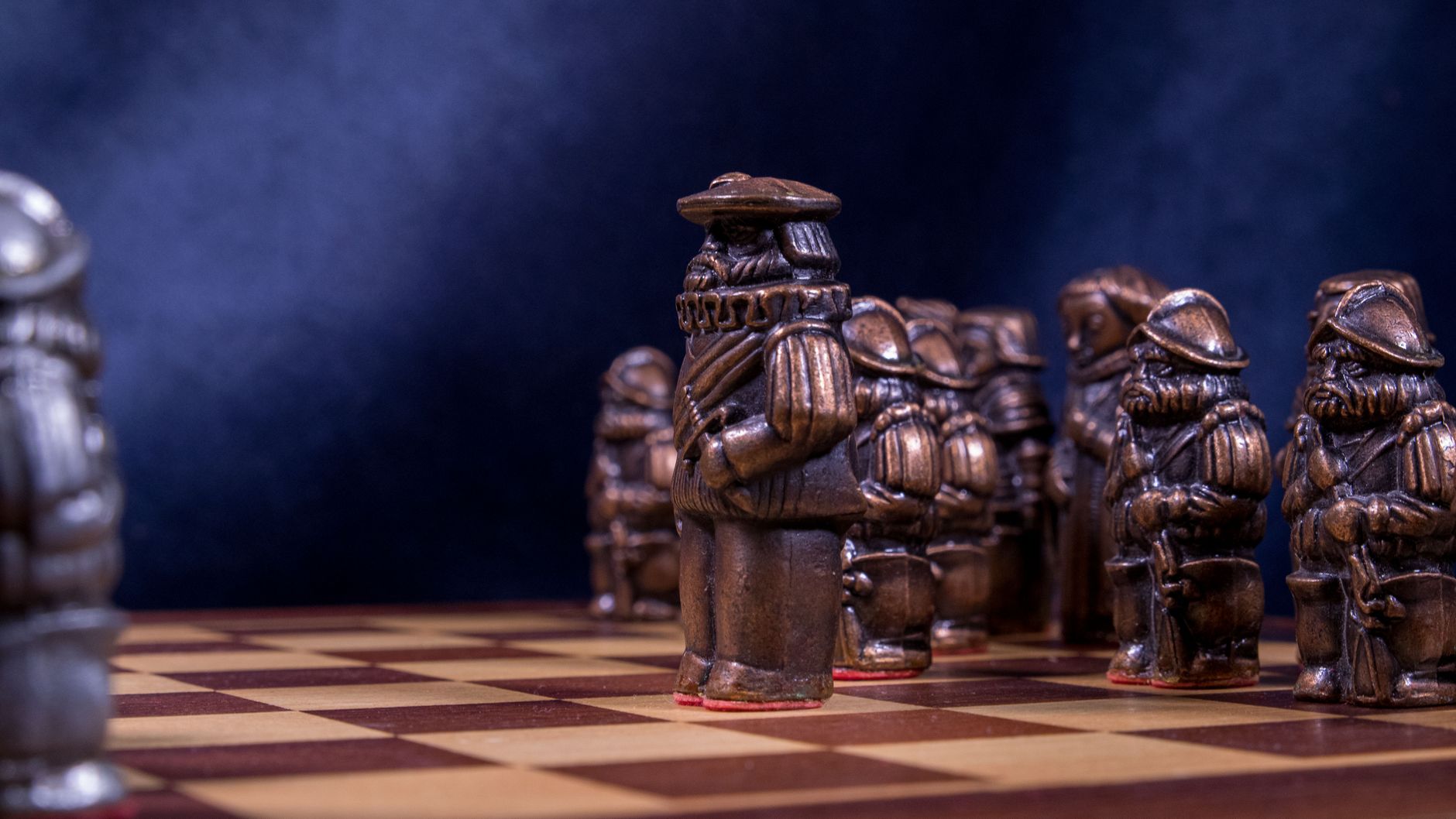 Close-up of a vintage chess set with intricately designed bronze pieces on a wooden board.