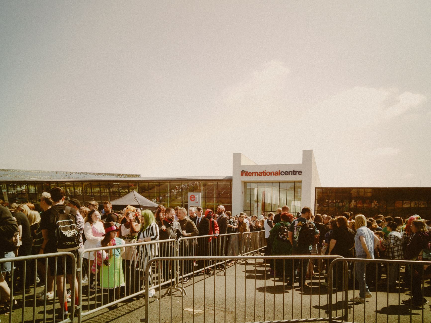 Large crowd gathering outside the International Centre under sunny skies.