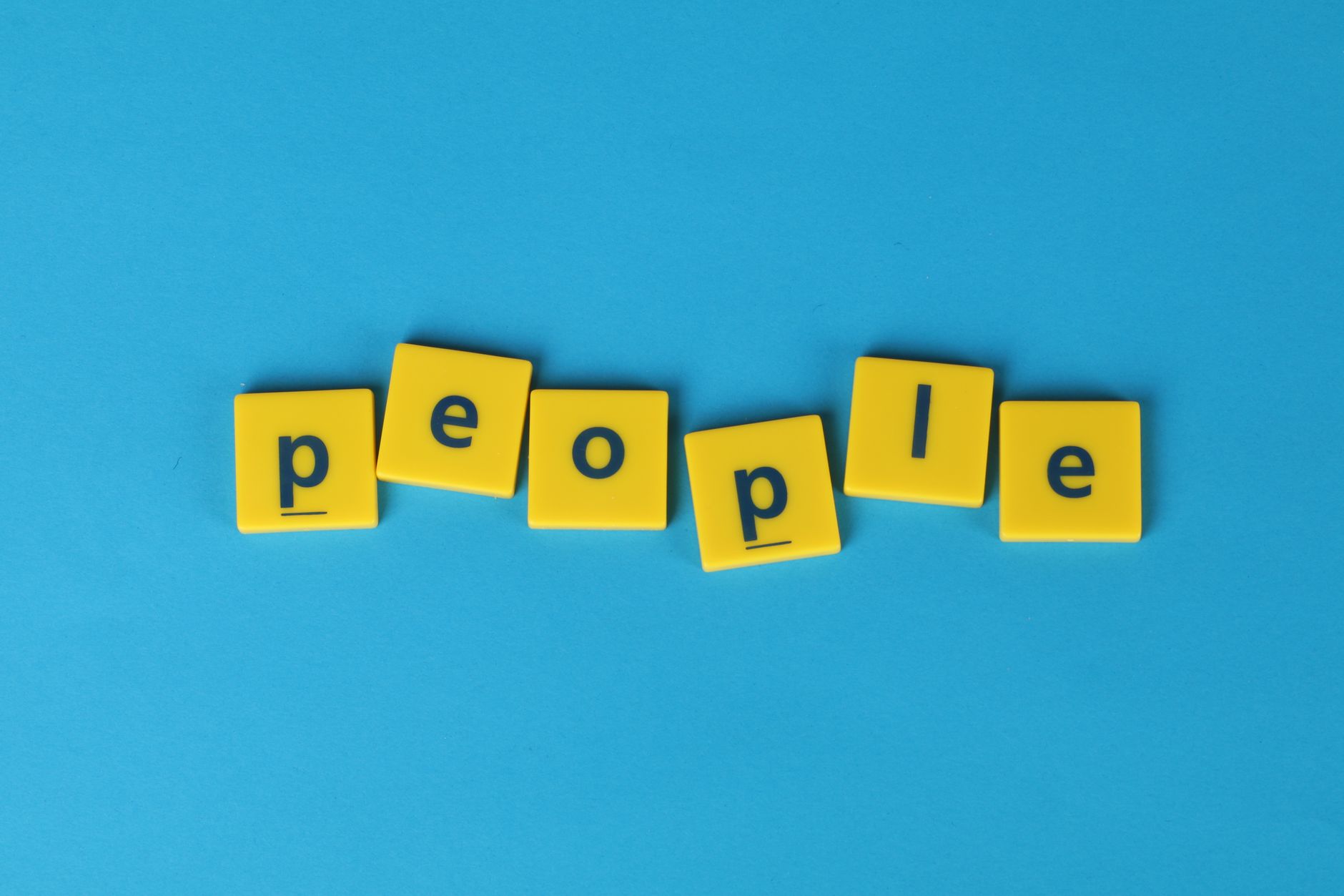Yellow Scrabble tiles spelling 'people' on a blue background, vibrant and playful.