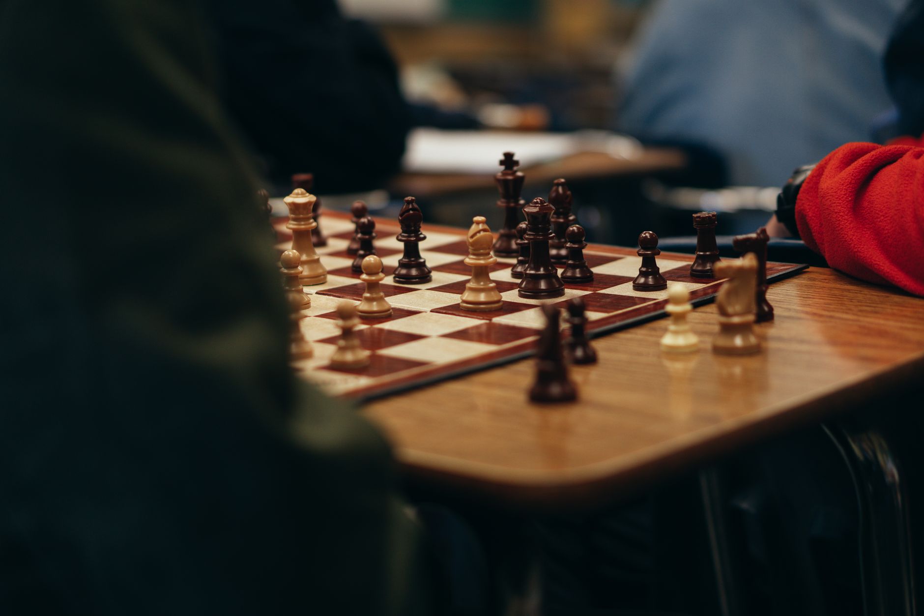High angle of crop anonymous people sitting at table and playing chess in club