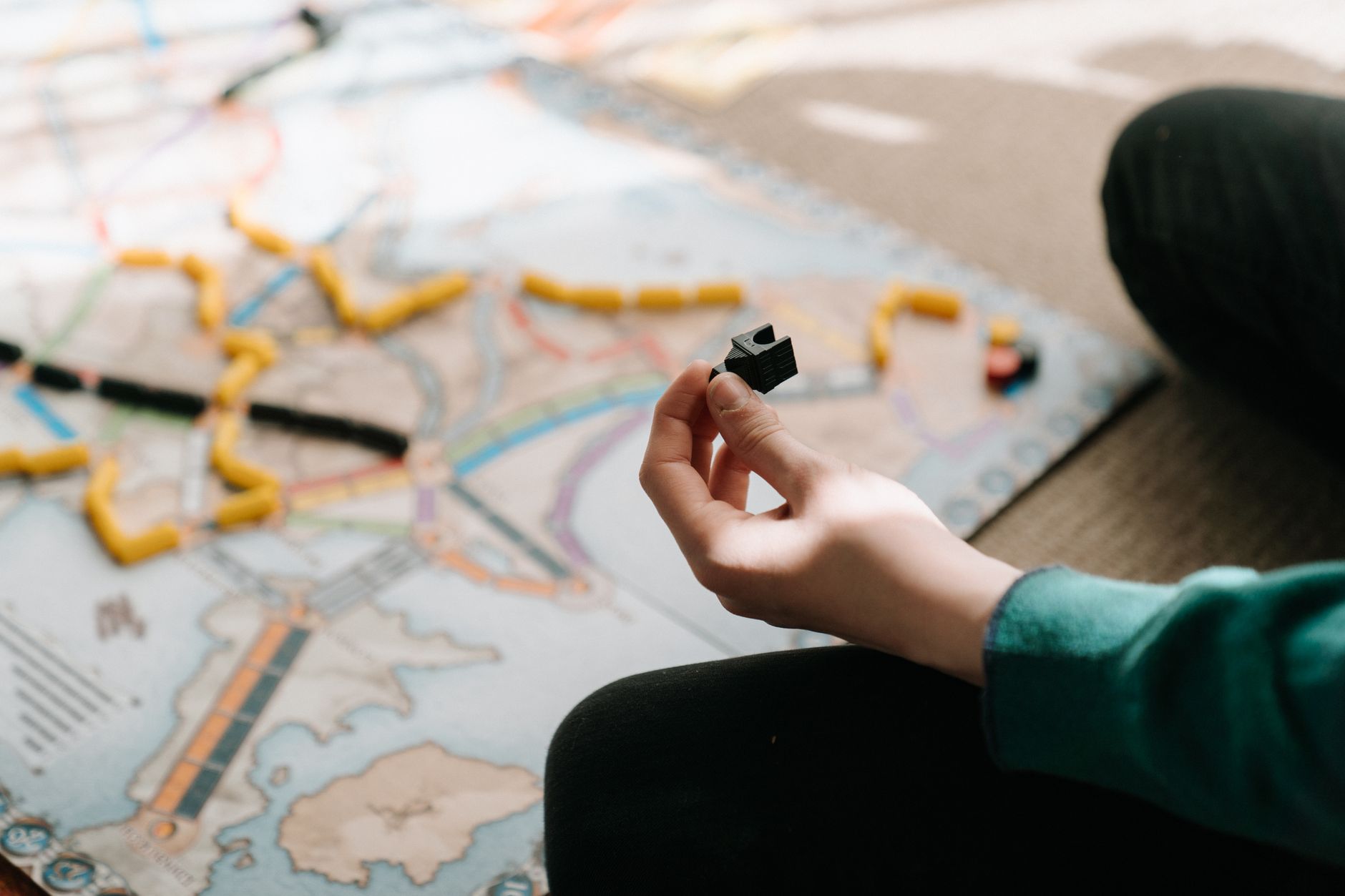 A person holding a game piece during a board game session indoors, showing strategy and leisure activity.