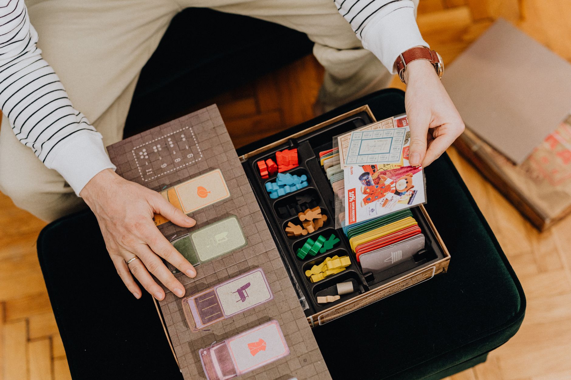 High-angle view of a person interacting with a vibrant board game full of cards and pieces.
