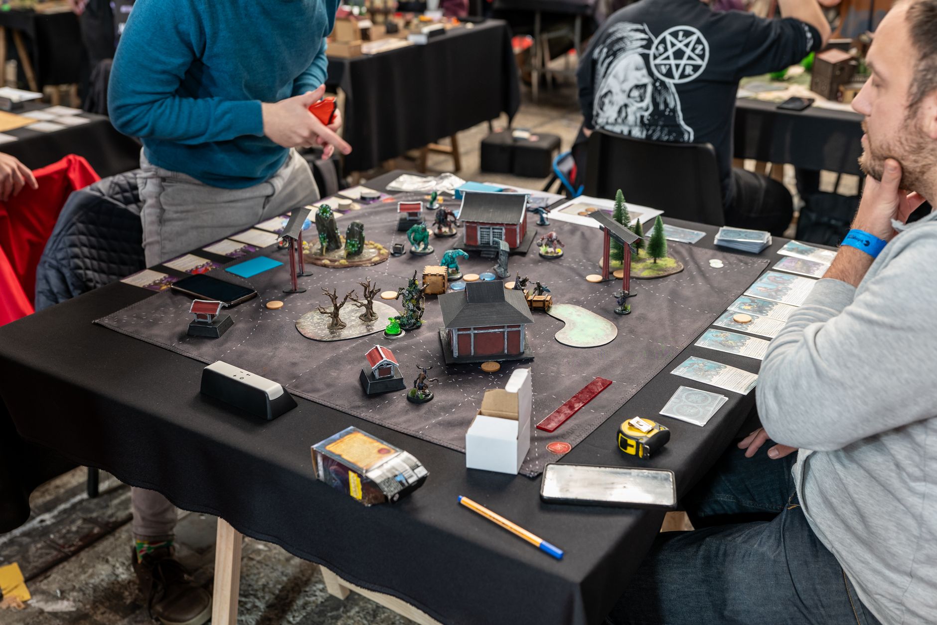 Players engaged in a tabletop miniature game tournament in Zagreb, showcasing strategy and teamwork.