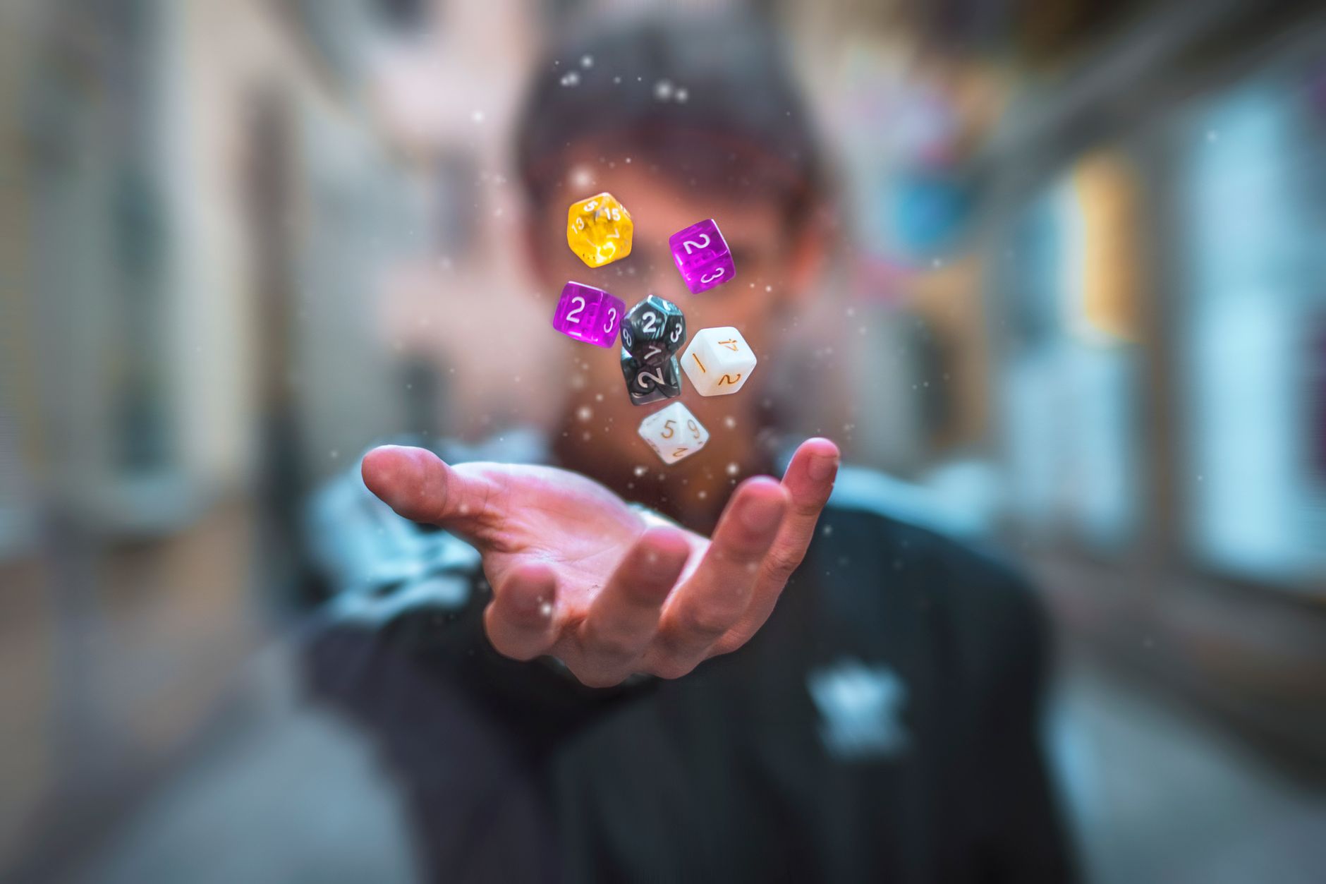 Colorful dice float above a hand with a blurred background, creating a dynamic and abstract visual.