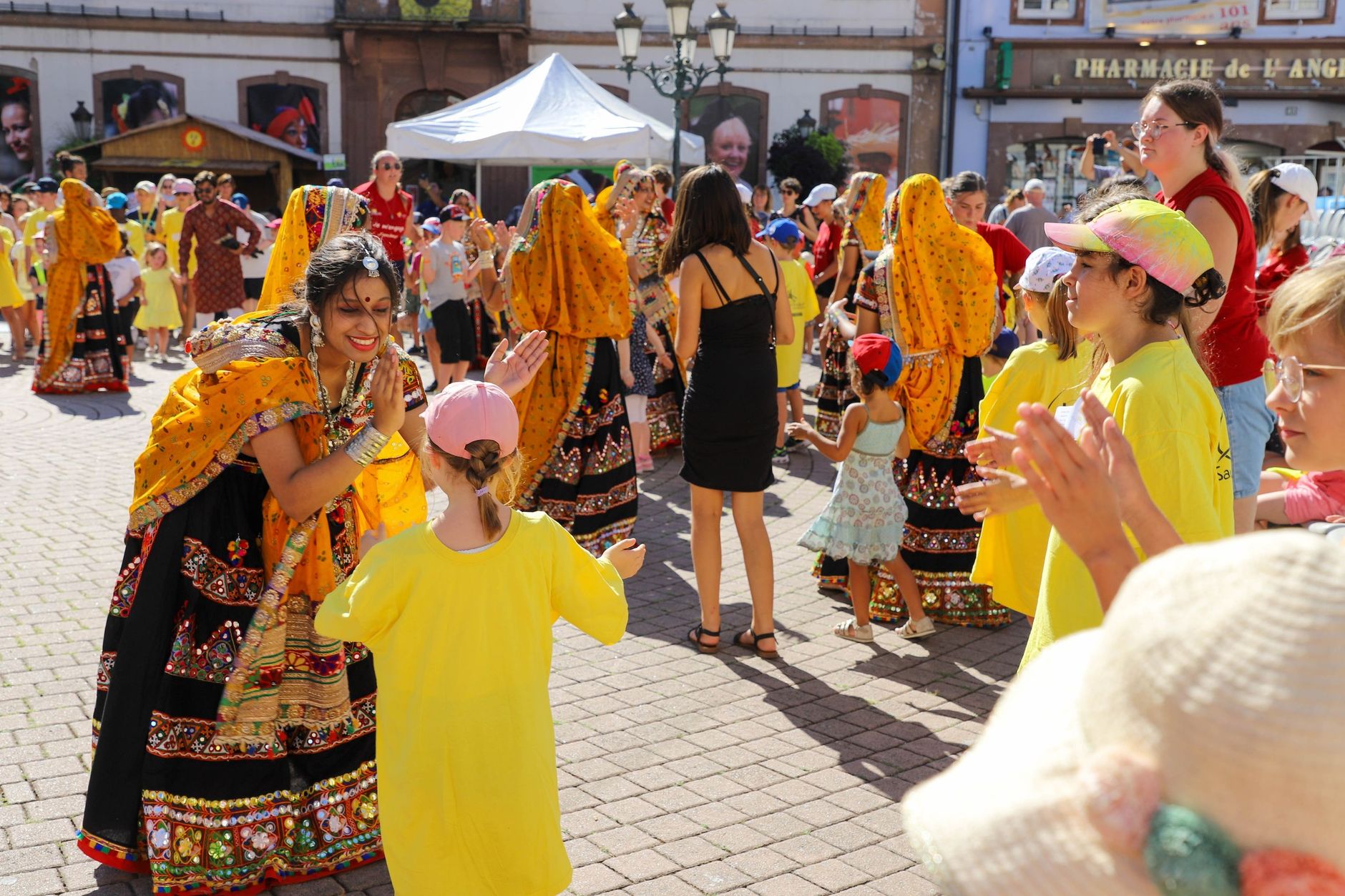 Joyful celebration with traditional dancers and children in colorful attire outdoors.