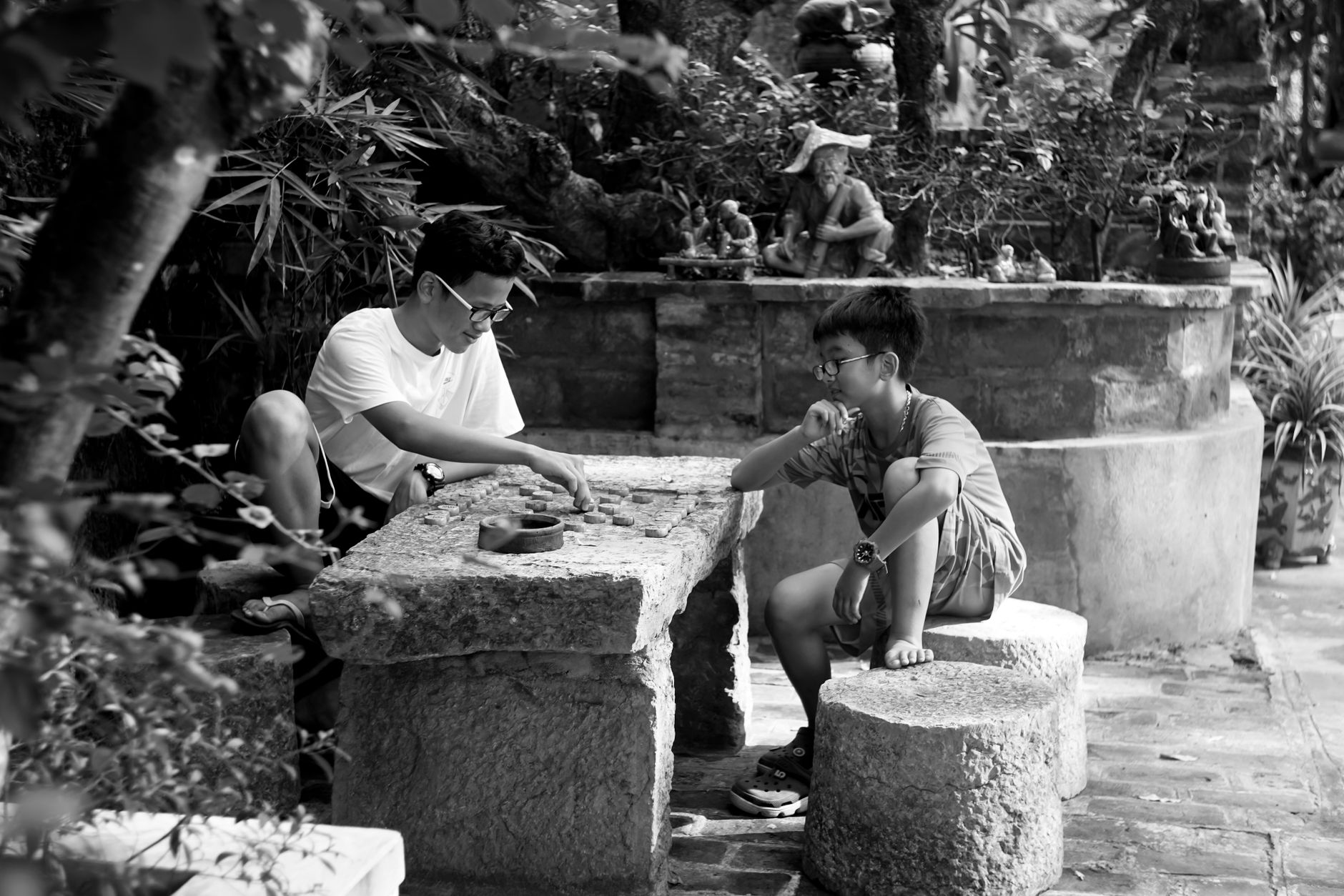 A father and son engaging in a board game activity in a serene outdoor setting.