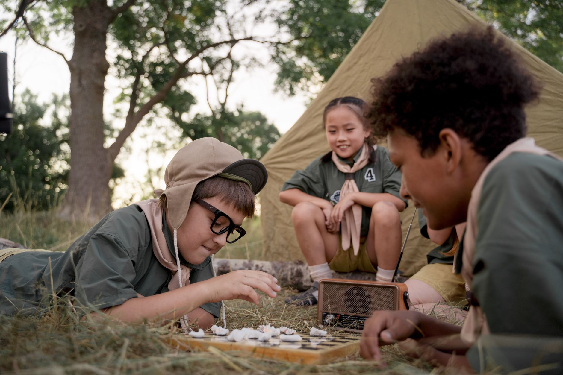 Group of kids playing a board game at a campsite, enjoying outdoor fun and togetherness.