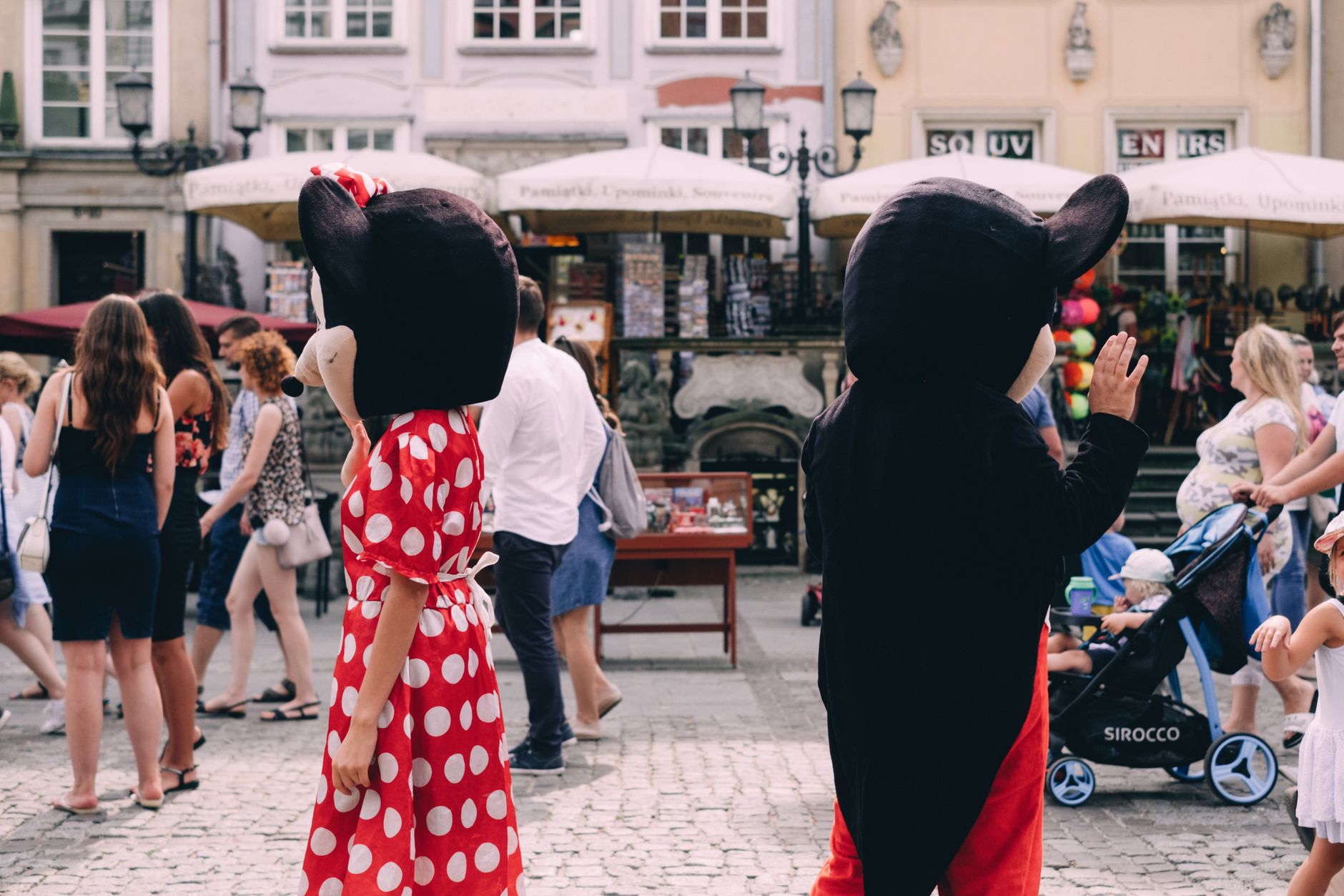 Costumed characters entertain a crowd on a sunny day in a vibrant outdoor setting.