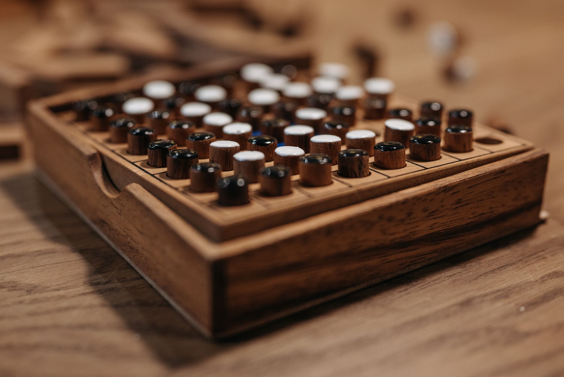 Detailed view of a wooden board game with black and white pieces, symbolizing strategy and leisure.