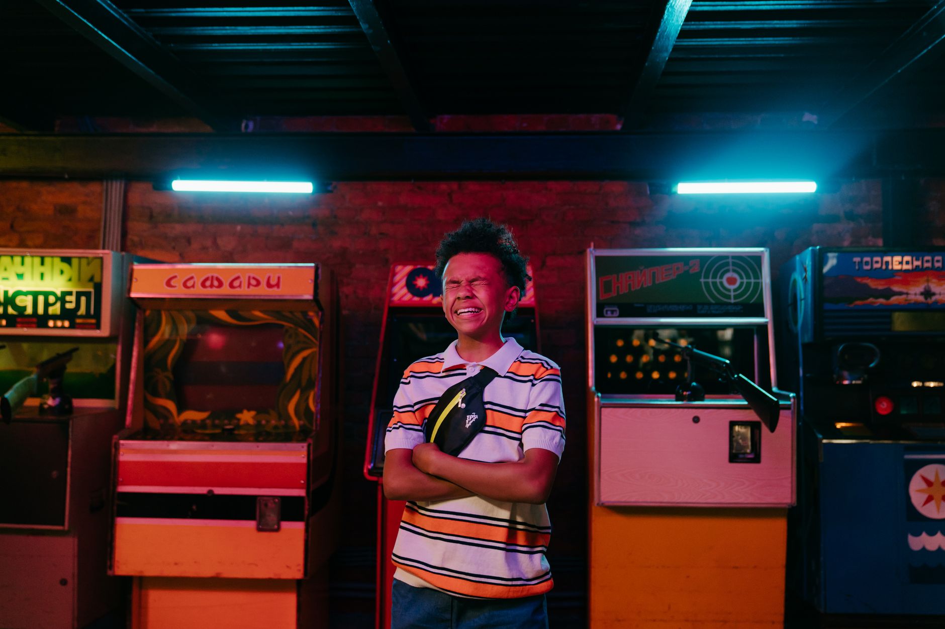 Smiling teenager enjoying a fun moment in a vibrant neon-lit arcade with classic game machines.