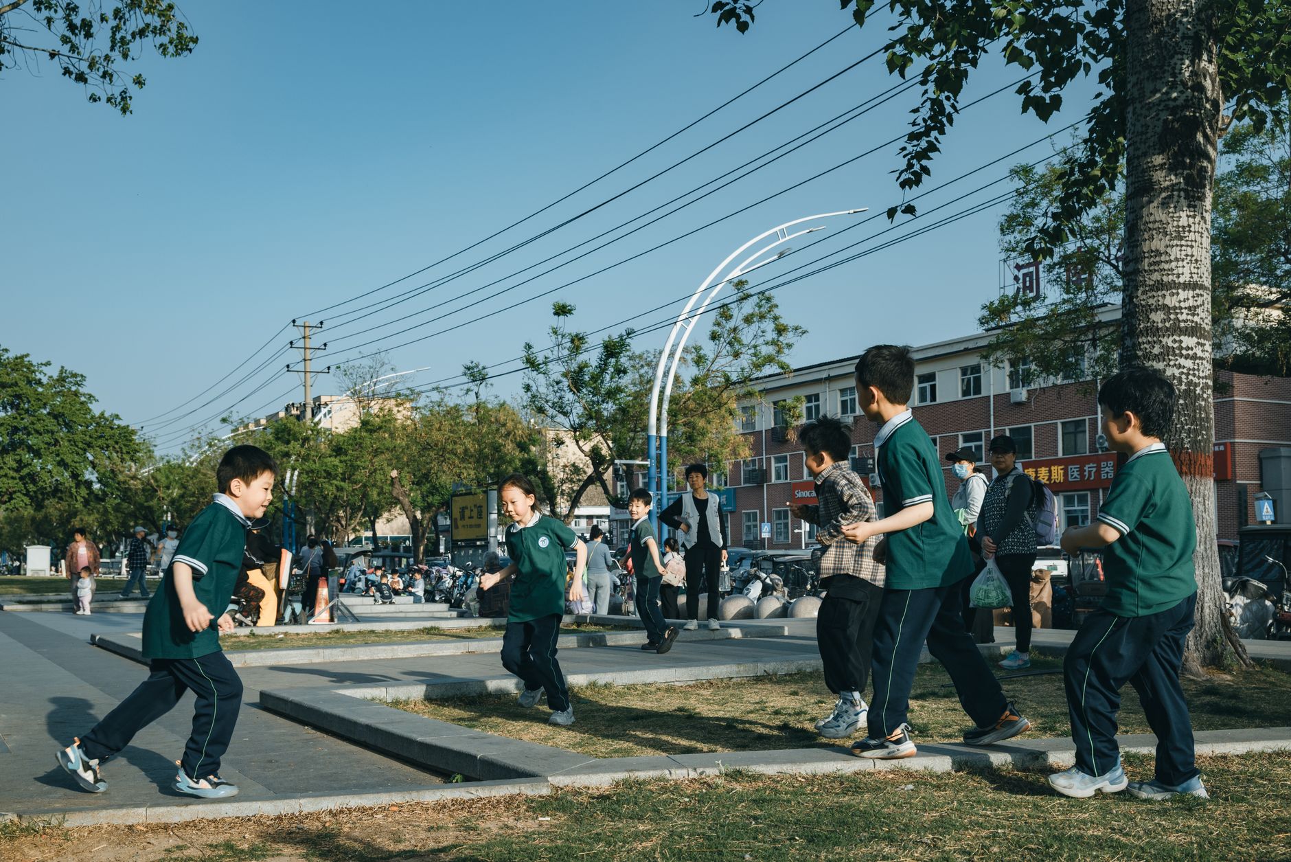 Group of children playing energetically in a sunny urban park area.
