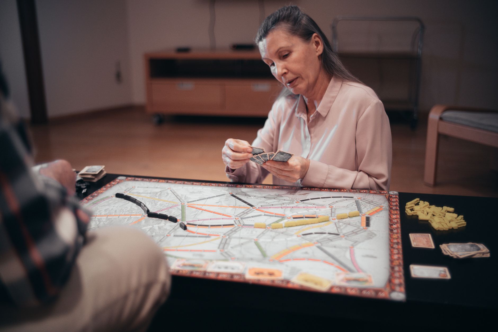 A woman focuses intently while playing a strategic board game indoors.