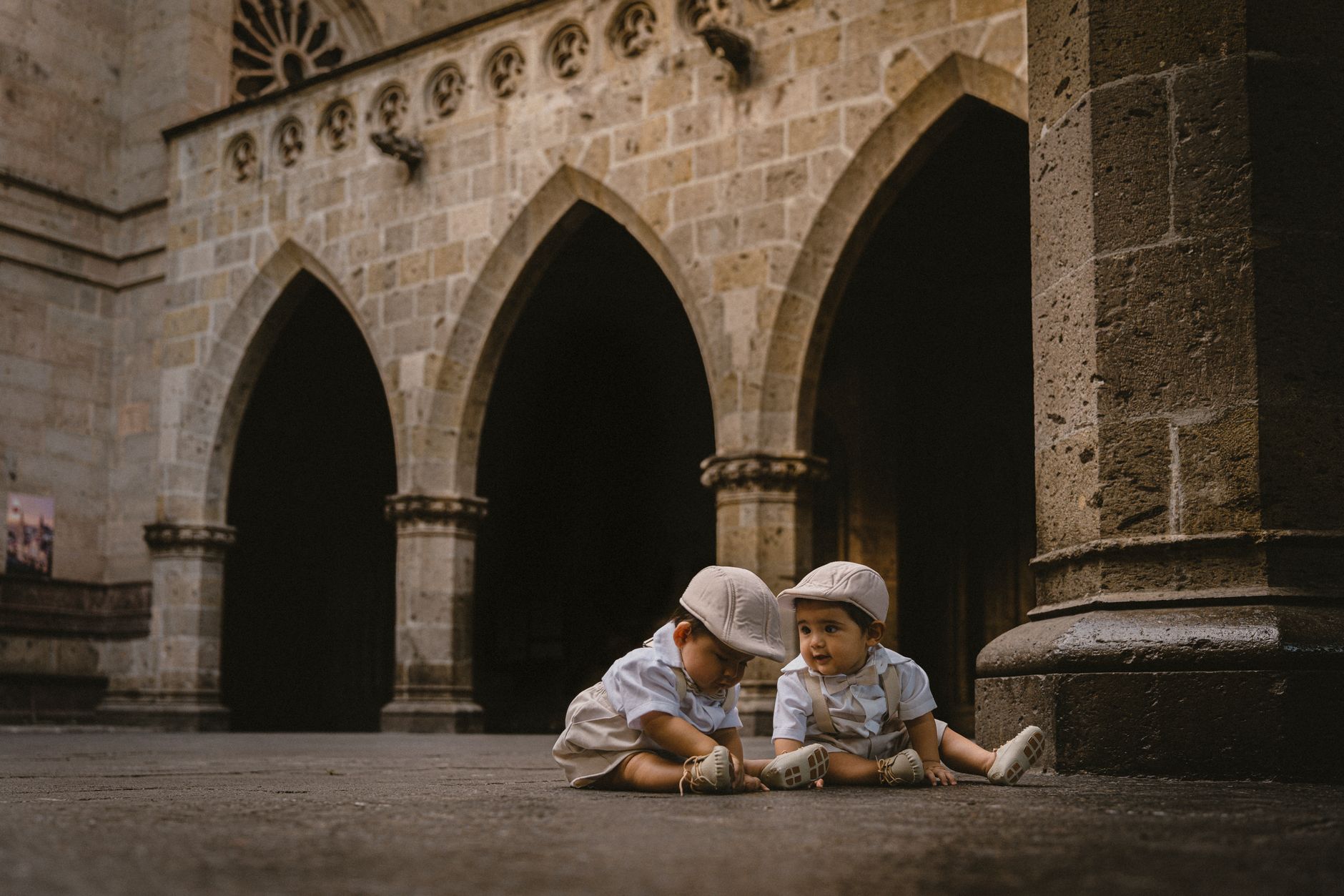 Two young boys in matching outfits play in an ancient courtyard, exuding charm and innocence.