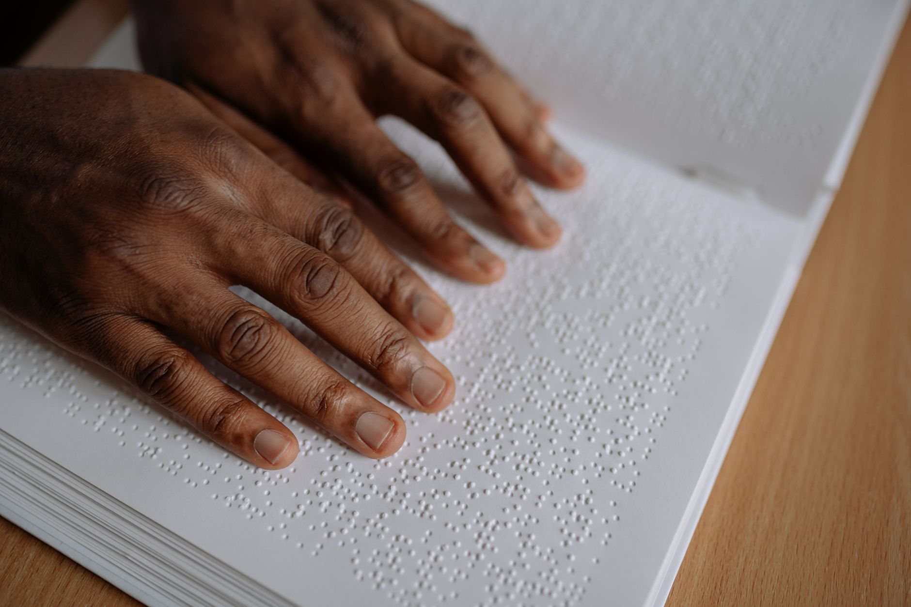 Close-up of hands reading Braille text on paper. Education and inclusivity concept.
