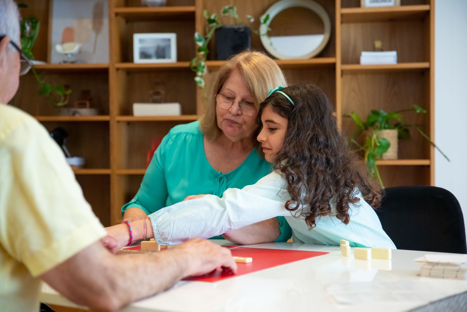 Grandparent and granddaughter playing board games at home, fostering a loving family bond.