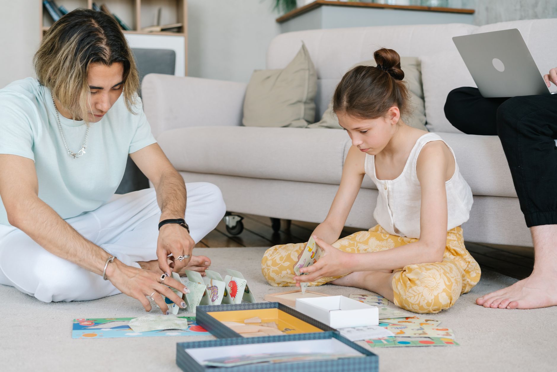A man and young girl playing a board game on the floor in a cozy living room setting.