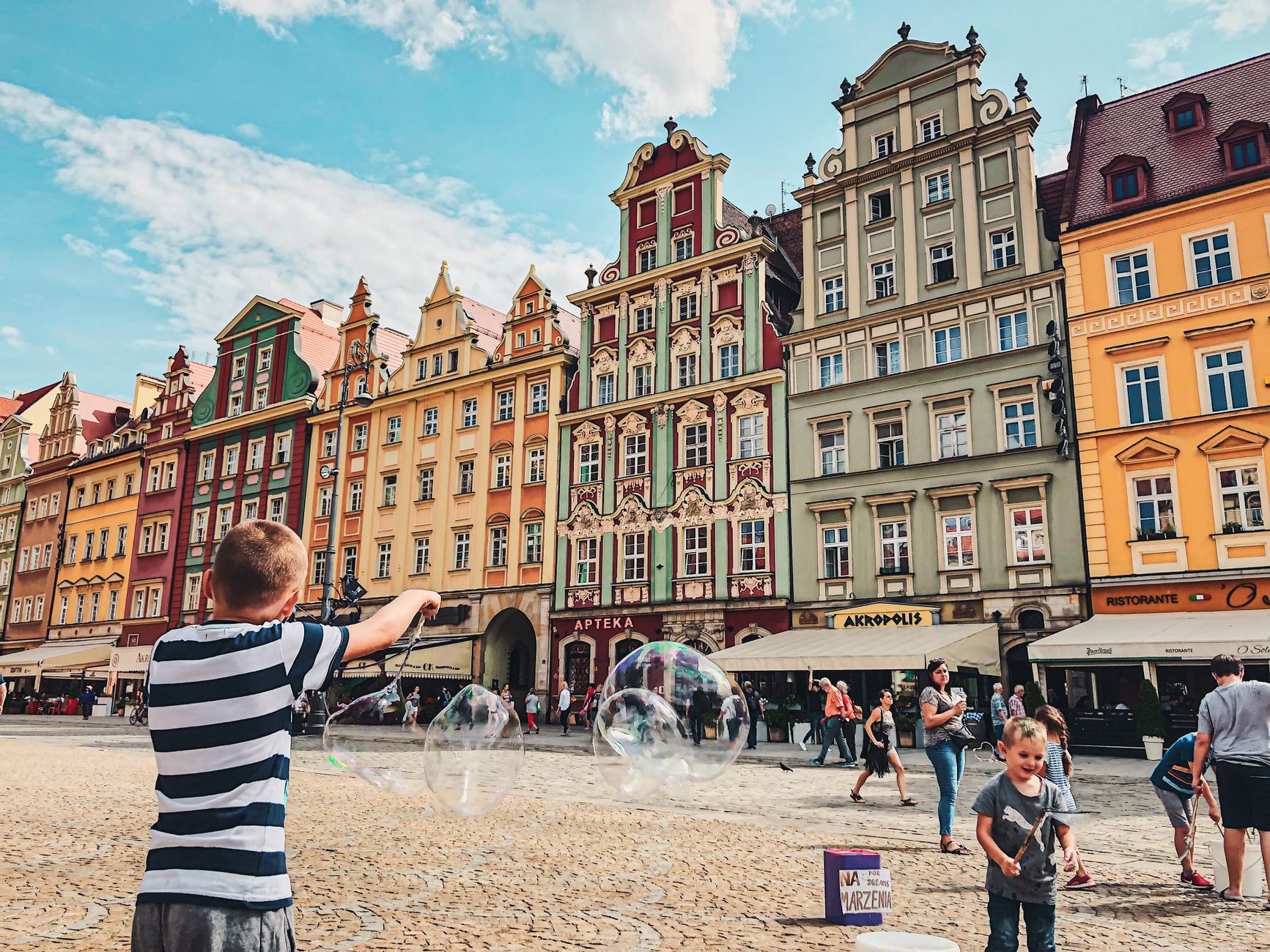 Vibrant city scene with children playing in Wrocław's historic market square.