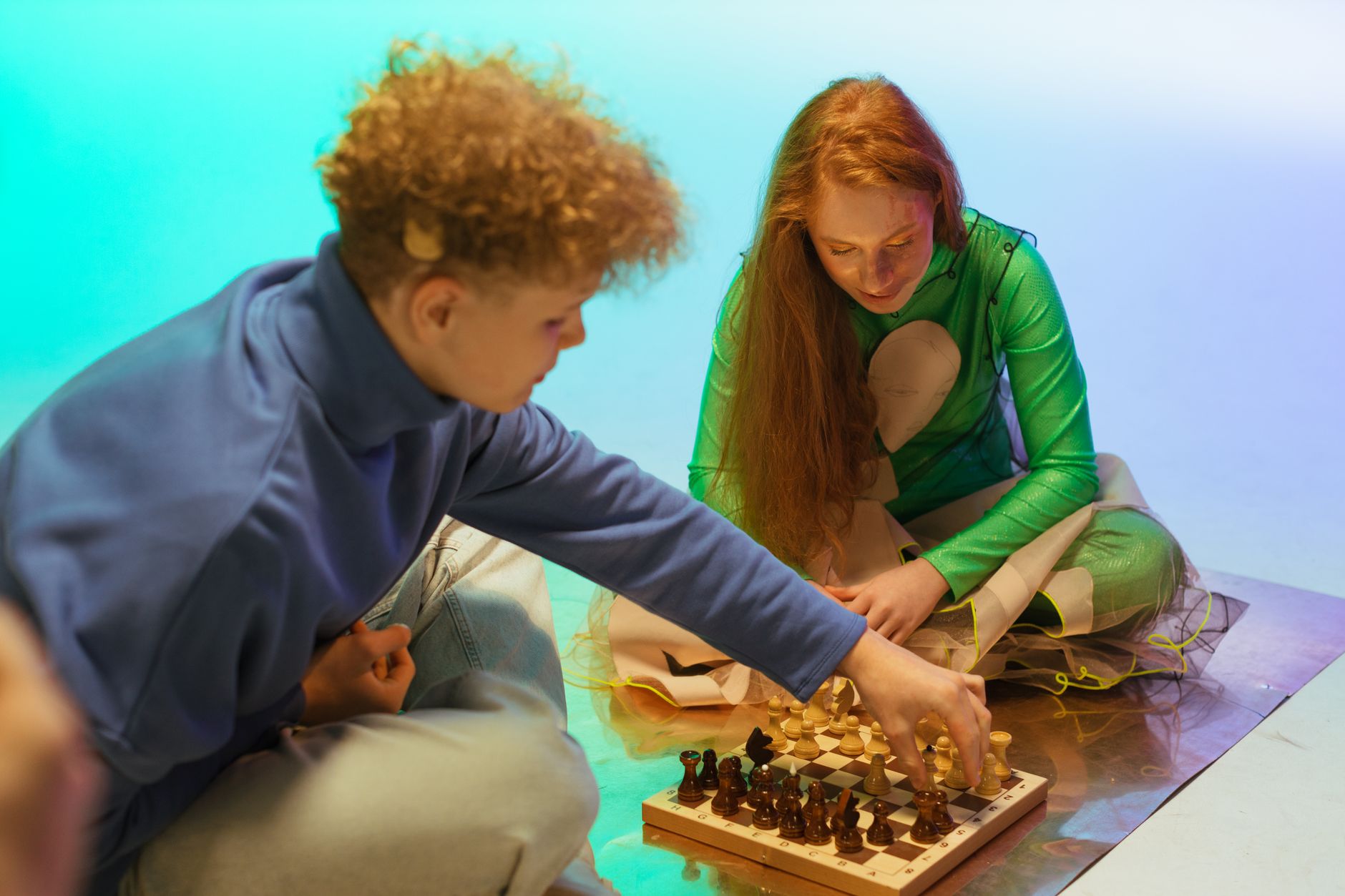 Two teenagers playing chess on a colorful indoor setup, focusing on strategy and fun.
