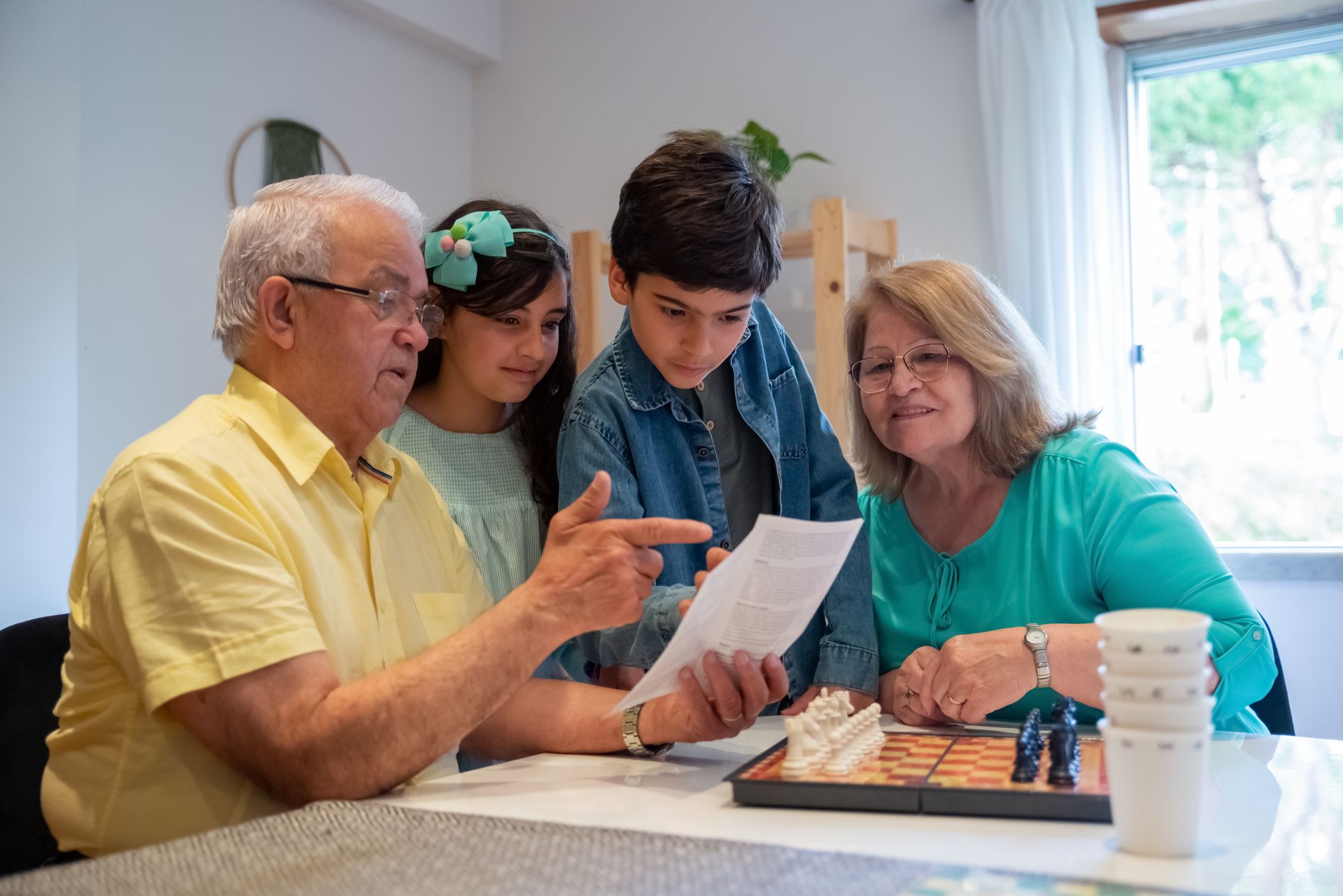 Grandparents teaching grandchildren to play chess in a cozy home setting.