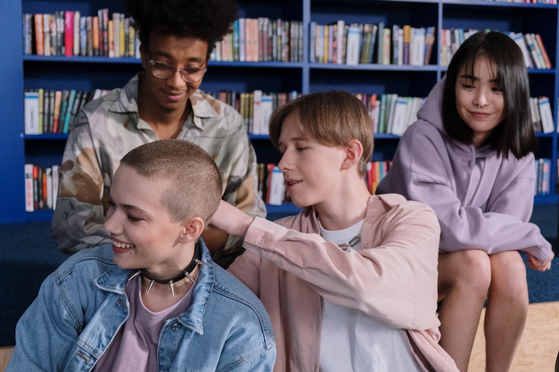 A diverse group of teenagers hanging out in a library setting, enjoying each other's company.